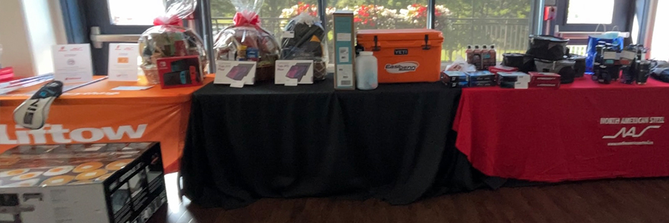 Tables laden with raffle prizes including a Nintendo Switch, Blackstone BBQ, Yeti Cooler, and a 32” TV at the charity event.