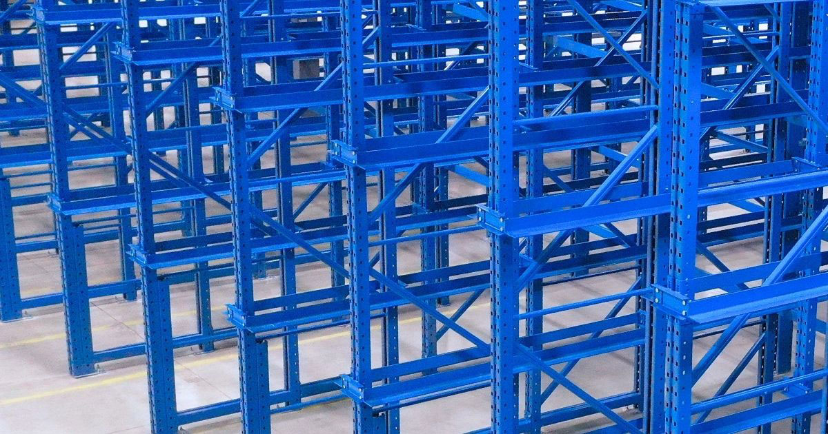 A close-up view of a high-density blue steel drive-in racking system featuring multiple vertical uprights and horizontal support rails designed for deep pallet storage.